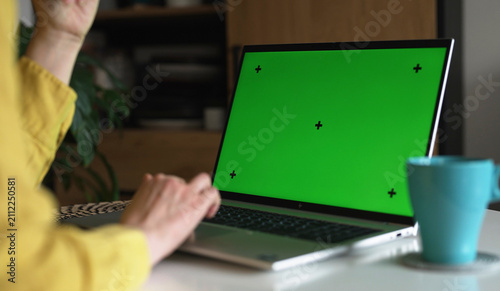 Laptop with green screen chroma key mockup for content replacement.