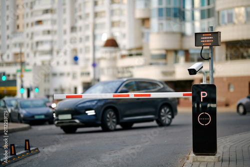 Automated access control barrier, surveillance camera system preventing vehicle entry into private parking area. Entrance security parking barrier arm down with cctv monitoring camera. Parking gate