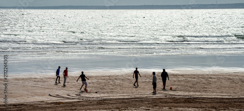 Seascape with silhouettes of young people playing football on beach of Essaouira. Morocco