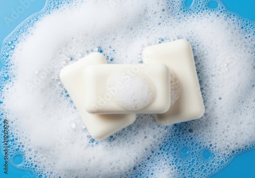 Three bars of white soap with lather on blue background