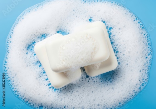 Three bars of white soap with lather on blue background