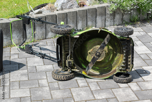 Lawn mower turned on its side for cleaning and drying.