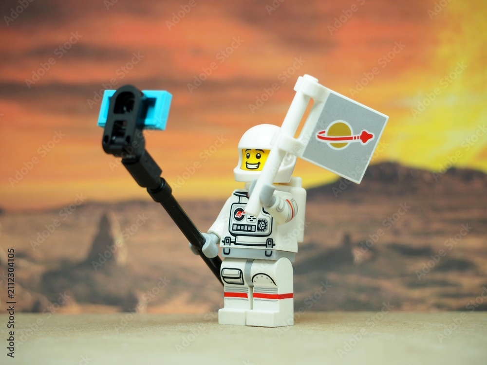 Naklejka premium Indonesia - June 17, 2025 : Mini toy of action figure at table with blurred background. Miniature diorama photography concept design. Astronaut character take a photo with alien at space. Selfie stick