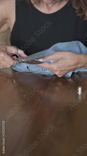 Hand sewing denim jeans hem with thimble scissors pins vertical
