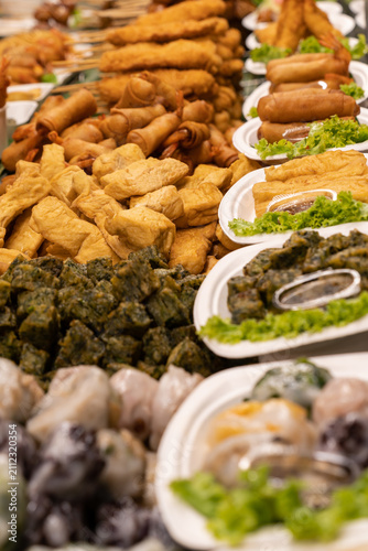 A colourful assortment of traditional fried snacks, spring rolls, stuffed tofu, seaweed rolls, and steamed dim sum displayed at a local food stall. 