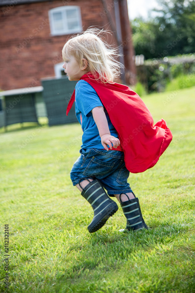 Fototapeta premium Child superhero playing outdoors joyfully