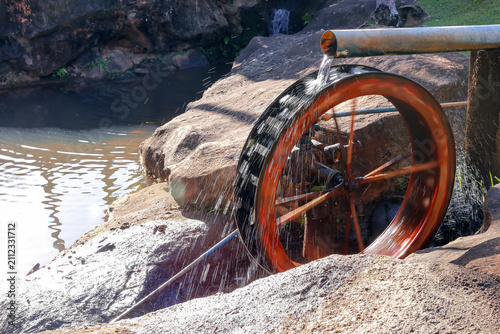 Rustic wooden water wheel operating in a traditional eco friendly hydraulic pumping system