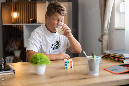 Fotografi Young boy making a funny face, puckering due to the sour taste while drinking ci