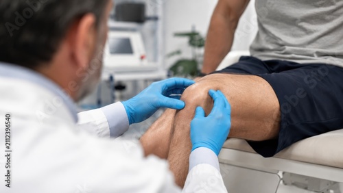 Orthopedic doctor examining patient's knee in medical clinic