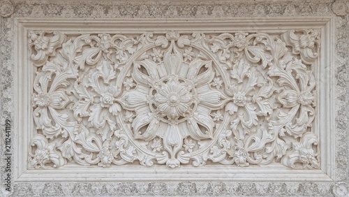 An ornate floral and leaf pattern carved in stone, forming a decorative rectangular panel.