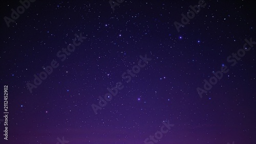 A clear night sky filled with stars seen against a dark purple background.
