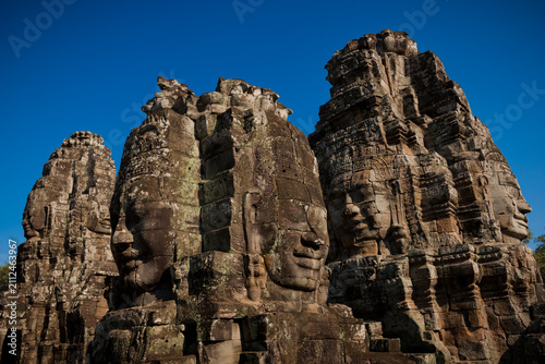 Ancient Bayon face towers beneath clear blue sky