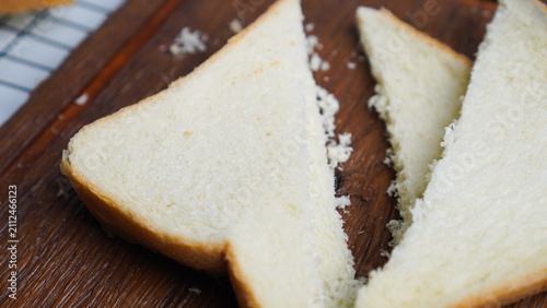 A slice of bread is cut in half and placed on a wooden cutting board