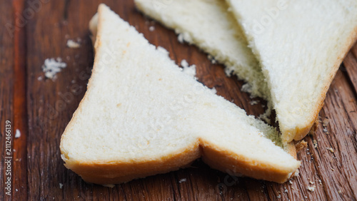 A slice of bread is cut in half and placed on a wooden cutting board