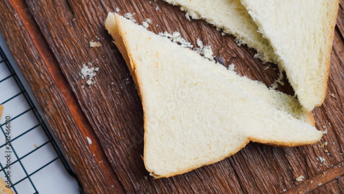 A slice of bread is cut in half and placed on a wooden cutting board