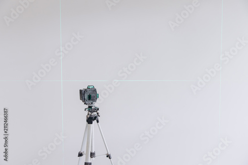 Foto Laser level tool projecting green cross lines on a white wall for precise measur