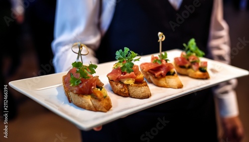 gourmet bruschetta appetizers served on a white platter by a waiter at a catering event or wedding reception