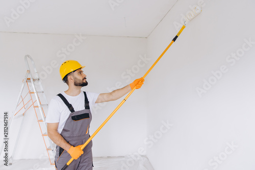 Bild auf Leinwand Professional painter renovating apartment, applying white paint with a roller on
