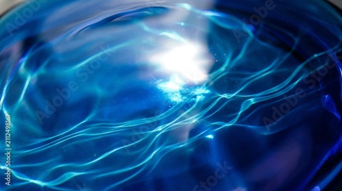 Luminous Blue Glass Surface with Ethereal Caustic Light: Bright Refracted Illumination, Polished Crystalline Material, Flowing Wave Patterns, Shimmering Highlights, and Vibrant Glowing Energy