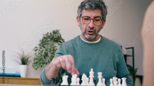 Video of mature man playing chess with a friend at home