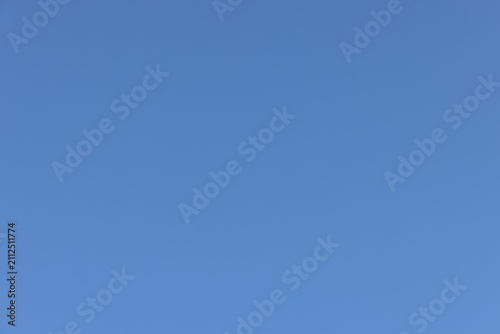 A plain cloudless blue sky fills the entire frame with an even natural gradient and clean central copy space for simple graphic design.