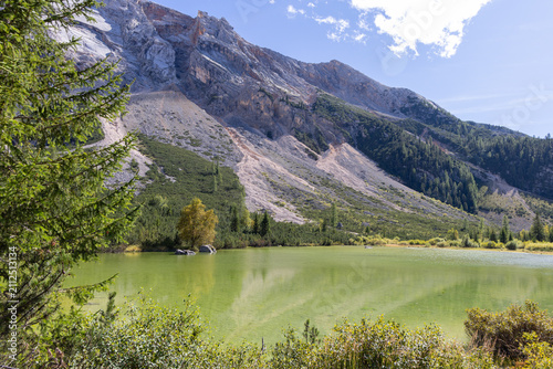 Canvas Print Green water of Le Piciodel lake lies below the limestone and scree face of Col Bechei, framed by spruce on the Fanes plateau in Italy
