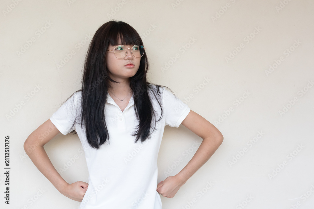 Obraz premium Serious young Asian Thai teenage girl in glasses and white polo shirt looking sideways.