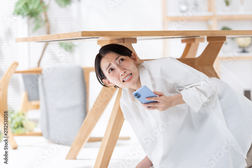 地震が起きてテーブルの下に隠れる女性