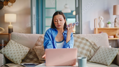 Bild auf Leinwand Cheerful freelancer talking speakerphone using laptop home living room sofa