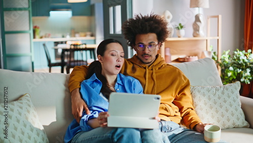 Fotografía Interracial couple browsing tablet on sofa at home