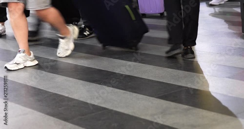 A white domestic dog on a leash with its owner near the baggage checkpoint at the train station entrance. Traveling with a pet.