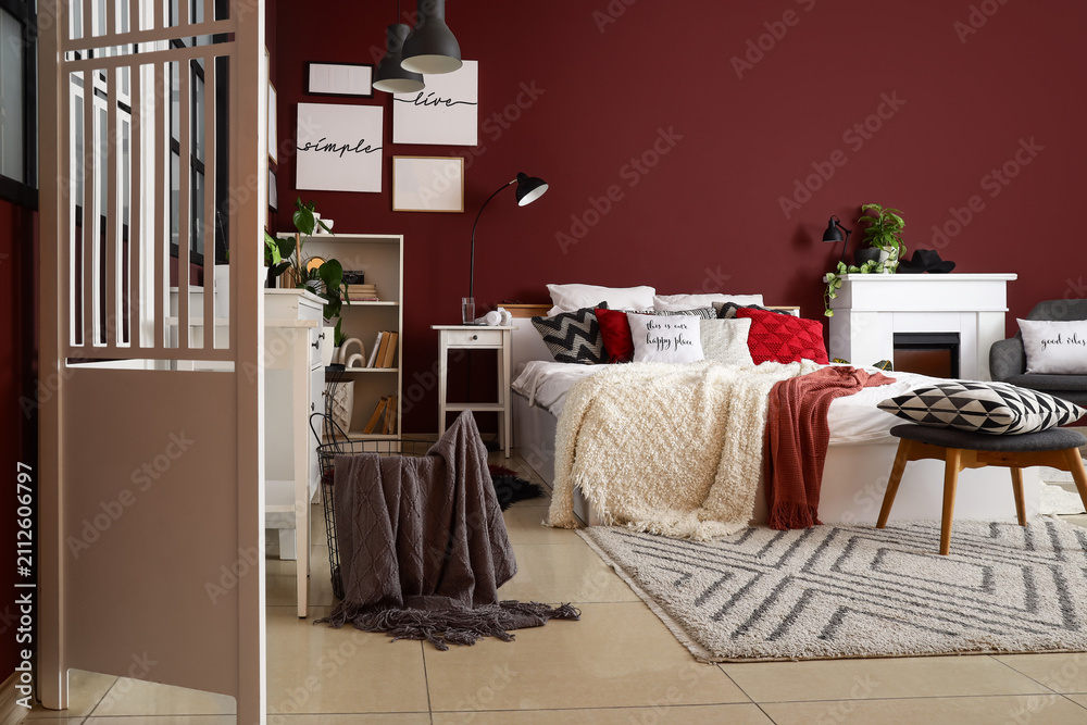 Obraz premium Interior of stylish bedroom with white folding screen, shelf unit and plants