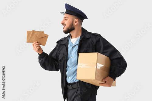 Handsome postman with letters and parcel on white background