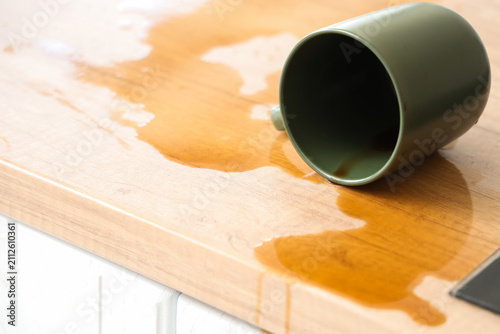 фотографія Overturned cup and spilled coffee on table in kitchen, closeup