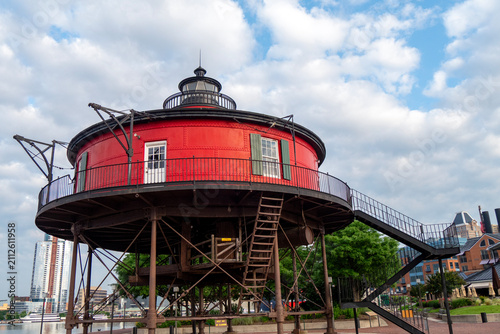 Lighthouse Beacon Tower on the Pier in Baltimore harbor with Blue Sky, Sea, Clouds and Modern Coastal Architecture for Navigation Safety
