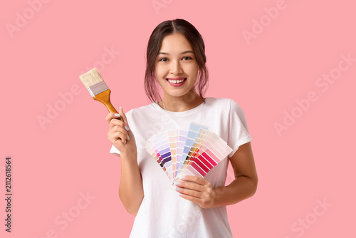 Bild auf Leinwand Beautiful young woman with paint brush and palette samples on pink background