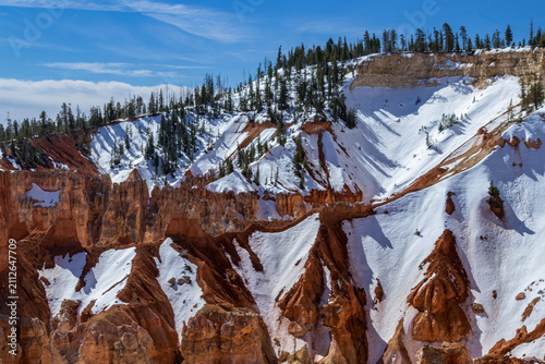 Snow and pine trees on a steep rocky canyon wall in Bryce Canyon National Park, Utah.
