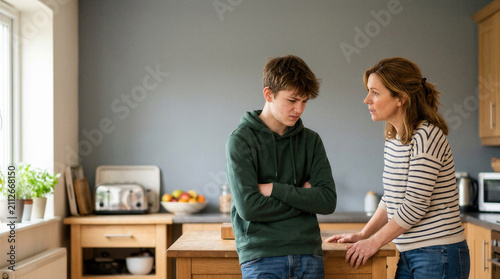 Mother talking to teenage son while standing in the kitchen  