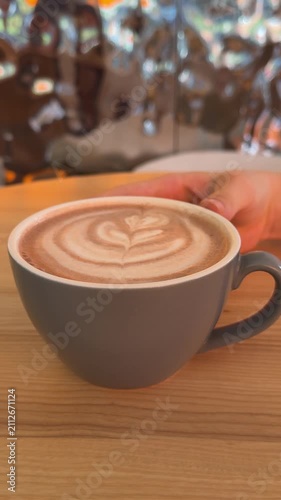 Freshly prepared milk coffee features smooth foam decorated with classic latte art, creating a warm and inviting drink for a relaxing coffee break. Close up.
