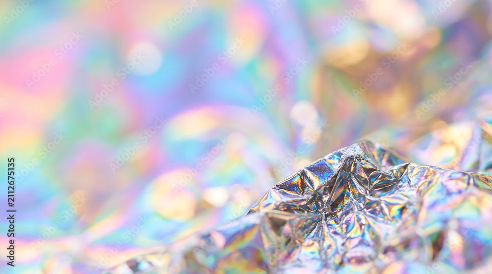 Fototapeta premium Shiny crumpled holographic foil texture with iridescent pastel rainbow colors and soft bokeh background