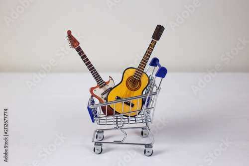 Photography Miniature acoustic and bass guitars inside a shopping cart representing musical