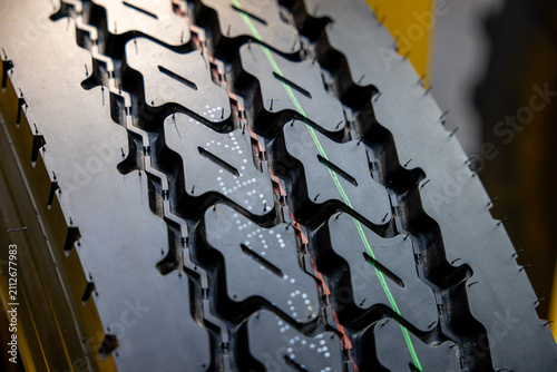 Detailed view of heavy duty truck tire tread with green and red marking lines. Professional industrial rubber surface pattern for commercial vehicle safety. High quality radial tyre component