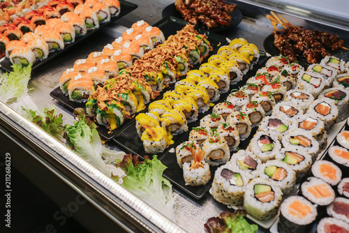 Fresh sushi assortment display. Japanese food background in restaurant counter. Colorful rolls selection. Seafood cuisine. Ready takeaway meal. Gourmet dining choice.