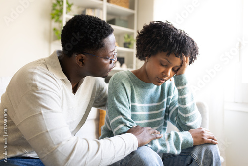 Man comforting sad woman at home on sofa