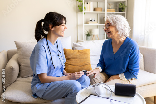 Nurse visiting elderly woman at home taking oxygen saturation level