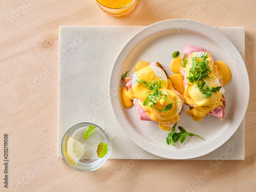 Egg benedict brunch on a white plate with drinks