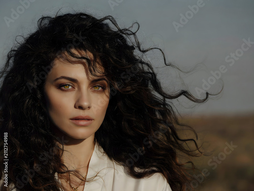 Cinematic portrait of a beautiful woman with flowing dark hair against a vast natural backdrop