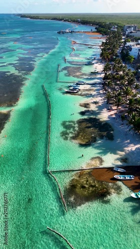 Vertical drone view of boats anchored on Mahahual beach with turquoise sea and sargassum barrier in Mexico on a clear day