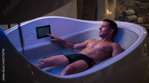 Man relaxing in a sensory deprivation tank with blue light