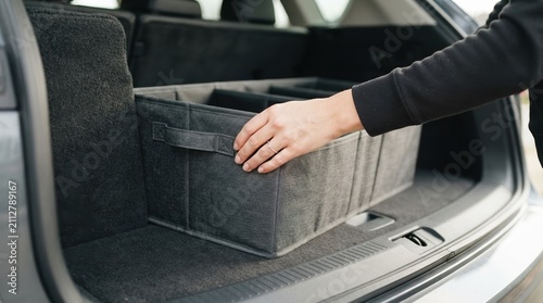 Woman organizing car trunk with a collapsible storage organizer box for road trip travel and cargo management